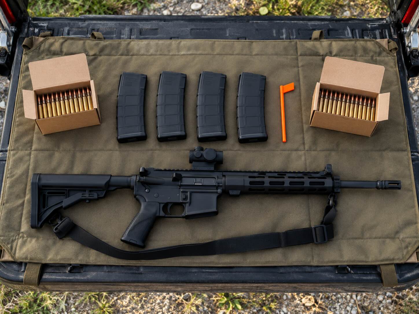 Gear for an AR-15 competition laid out: rifle with sling, magazines, chamber flag, and ammunition