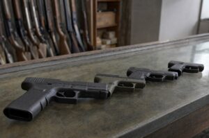 Several unbranded handguns laid out on a gun shop counter for someone buying their first gun