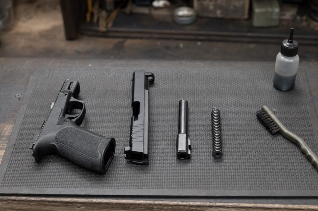 A field-stripped striker-fired pistol with slide, barrel and spring on a cleaning mat